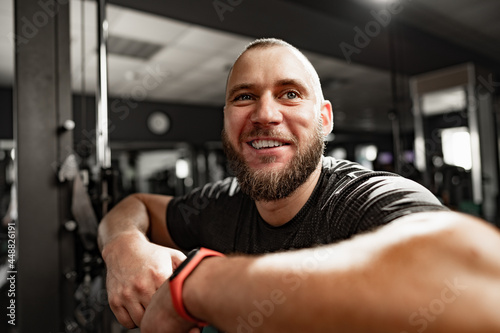 Cheerful smiling man bodybuilder standing in a gym