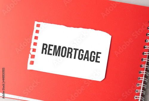 The word remortgage on torn paper on red notepad,. photo