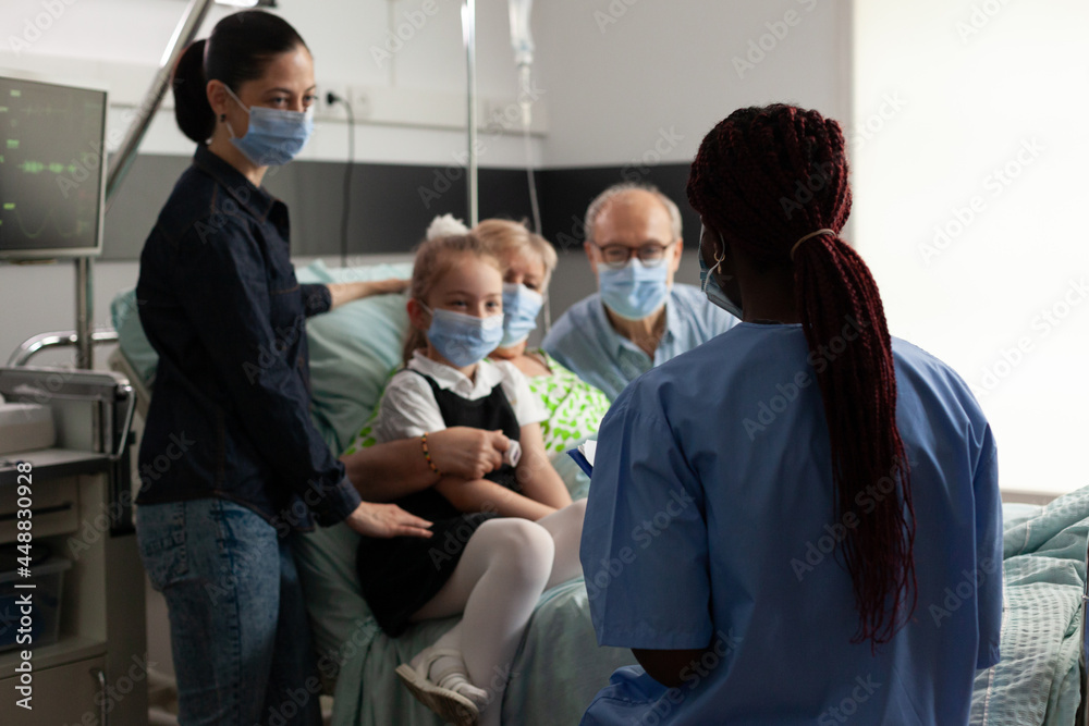 African american nurse monitoring elderly senior woman after clinical surgery in hospital ward. Caring family wearing medical face mask against covid19 while visiting patient during recovery African american nurse monitoring elderly senior woman after clinical surgery in hospital ward. Caring family wearing medical face mask against covid19 while visiting patient during recovery
