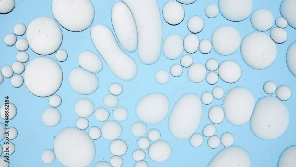 Light grey different sized bubbles move in circles on pale blue background | Background for skincare product with hyaluronic acid promotion shot