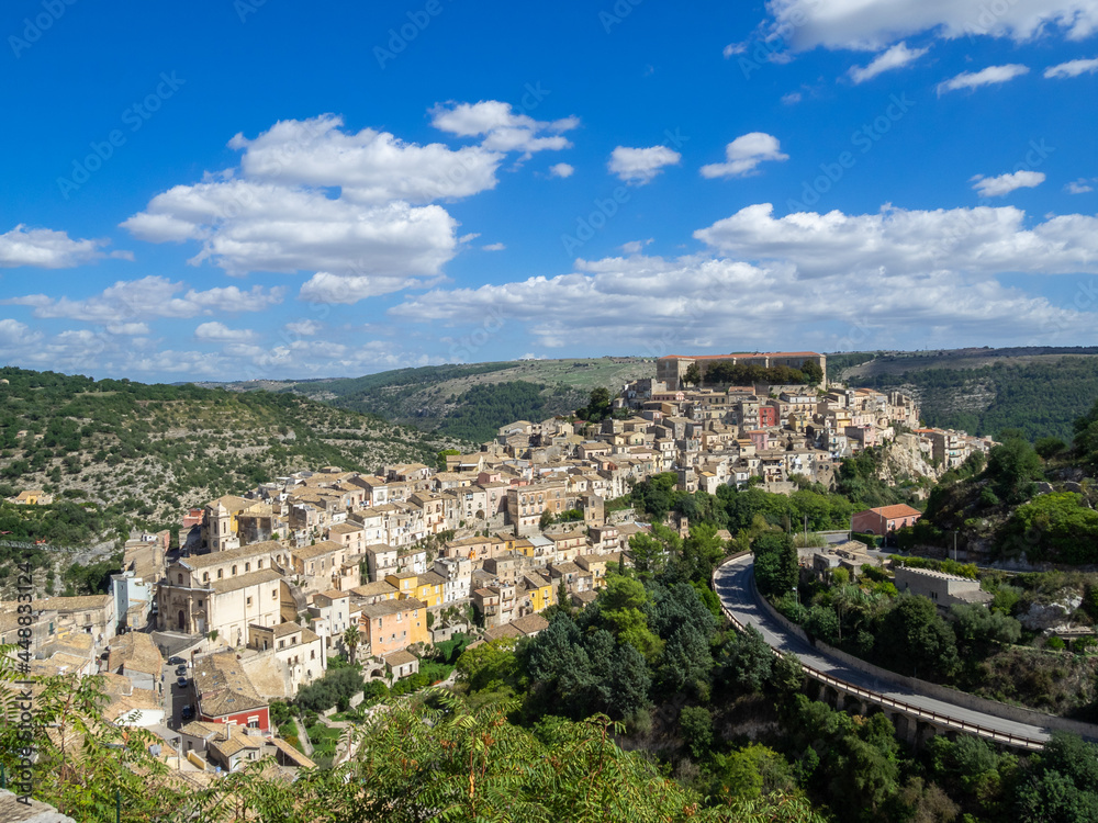 Ragusa Ibla between the green mountains and the blue sky over Valle dei Ponti