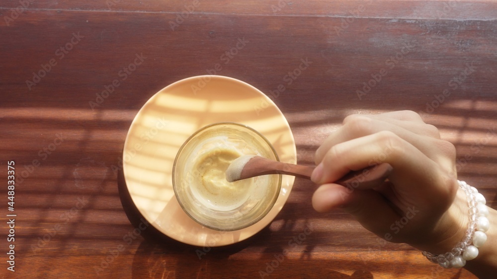 Elegant female hand stirring affogato coffee with a wooden spoon. Delicious morning caffeine drink for a woman. Avogato in the golden light through shutters on a wooden table. Lady enjoying beverage. Elegant female hand stirring affogato coffee with a wooden spoon. Delicious morning caffeine drink for a woman. Avogato in the golden light through shutters on a wooden table. Lady enjoying beverage.