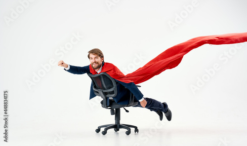 a man with a red raincoat rolls around in an office chair manager superman