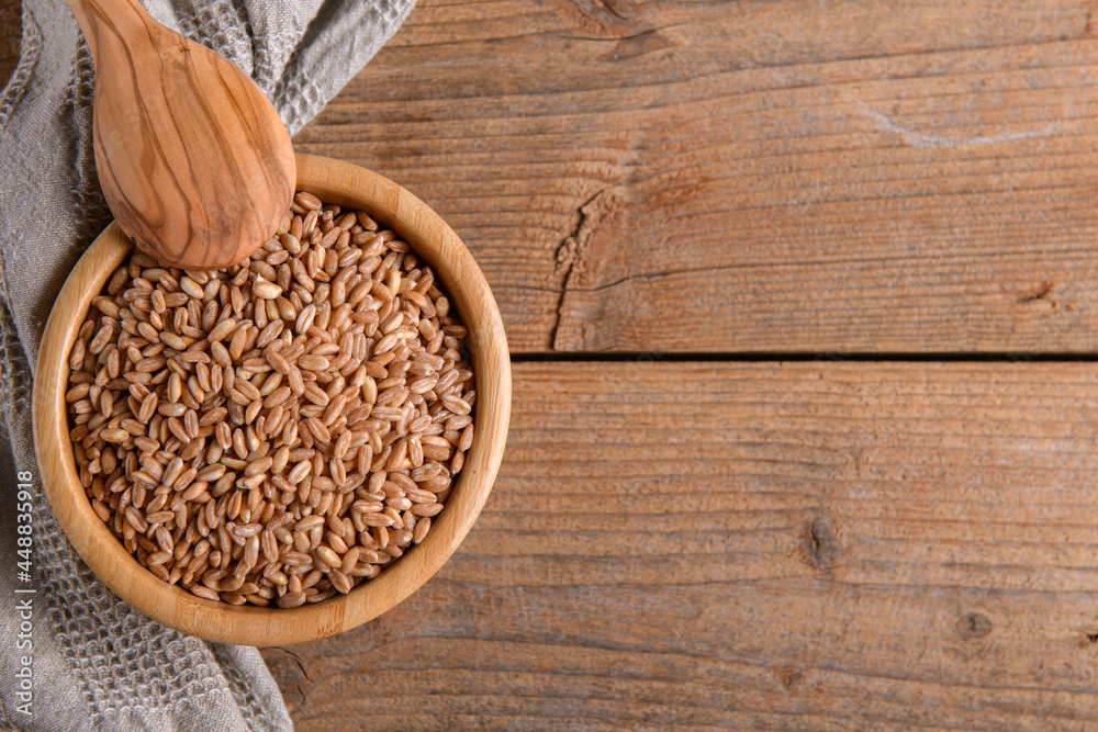 Wholegrain uncooked raw spelt farro in bowl on the wooden background Wholegrain uncooked raw spelt farro in bowl on the wooden background
