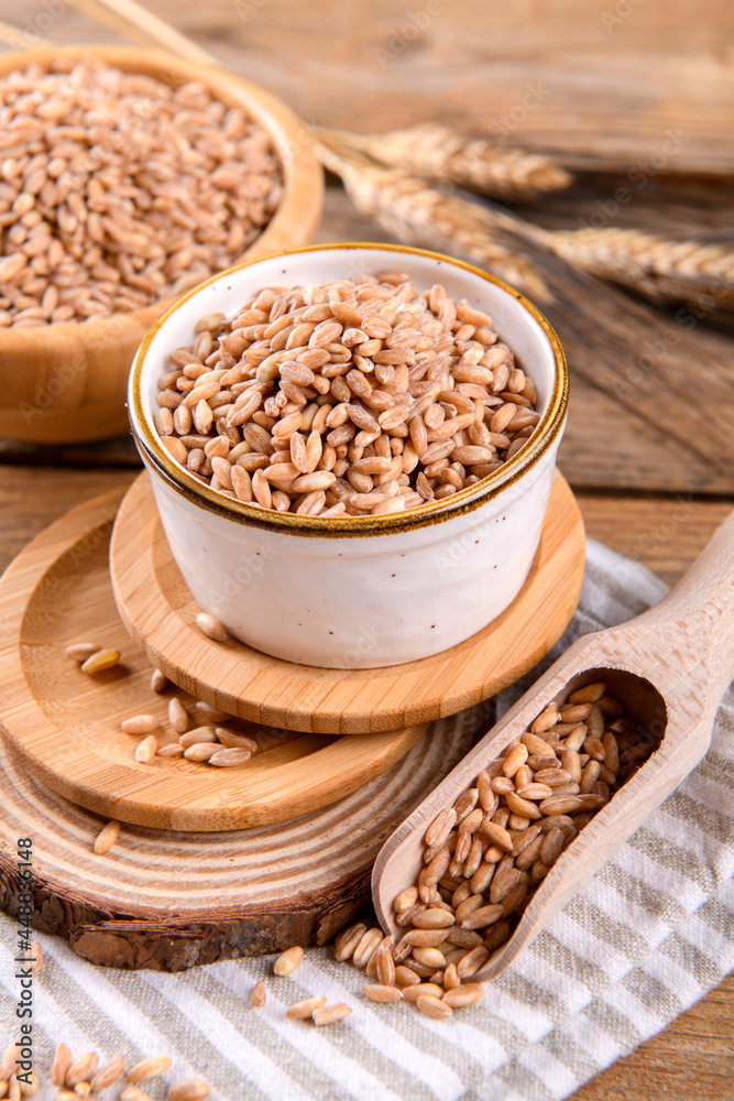 Wholegrain uncooked raw spelt farro in bowl on the wooden background, food cereal background, close up Wholegrain uncooked raw spelt farro in bowl on the wooden background, food cereal background, close up