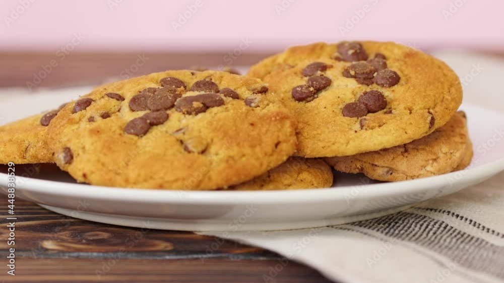 Pile of chocolate chip cookies on white plate on wooden table Pile of chocolate chip cookies on white plate on wooden table