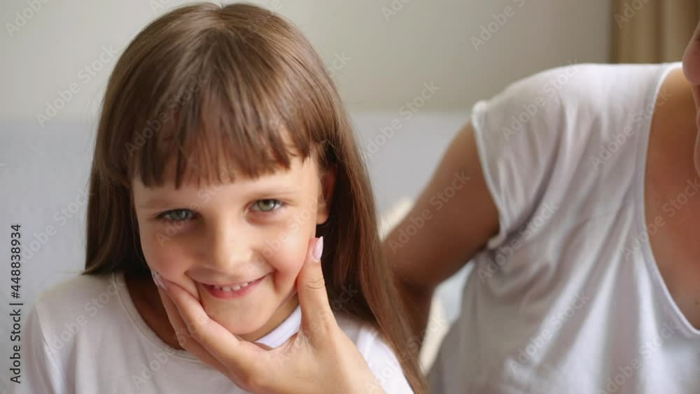 Funny little girl having fun with mother, mommy touching girls cheeks and making smile with hand, dark haired kid looking at camera, family wearing casual clothing. Funny little girl having fun with mother, mommy touching girls cheeks and making smile with hand, dark haired kid looking at camera, family wearing casual clothing.
