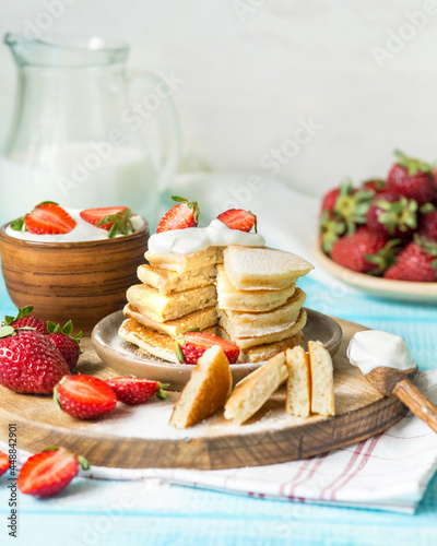 American breakfast. Pancakes with butter cream and strawberries. Berry dessert with milk. Summer breakfast with fresh berries