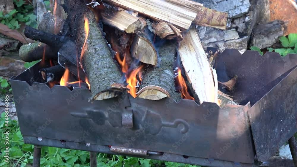 Campfire burning with smoke in the barbecue grill on nature. Firewood burns in the brazier. Campfire burning with smoke in the barbecue grill on nature. Firewood burns in the brazier.