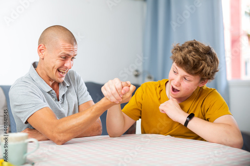 Father and his son doing arm wrestling on table © JackF