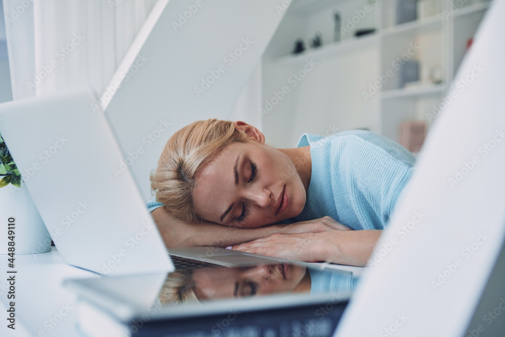 Tired young woman sleeping while sitting at her working place in office Tired young woman sleeping while sitting at her working place in office