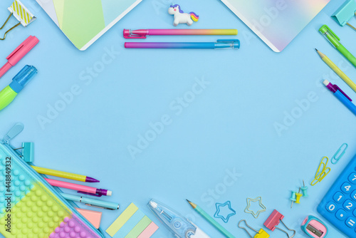 Back to School frame with copy space. Collection of colorful school supplies in a bright flat style. Educational concept. Unicorn, calculator, pencil case, pencils, sharpeners and curly paper clips.