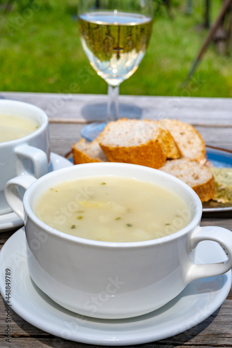 Lunch with homemade white asparagus soup and Dutch white wine served outdoor on green meadow with vineyard, asparagus and wine production farm in Netherlands
