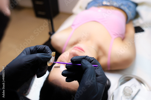 the girl is a master of lamination of eyelashes sitting at the head of the model and preparing for the procedure