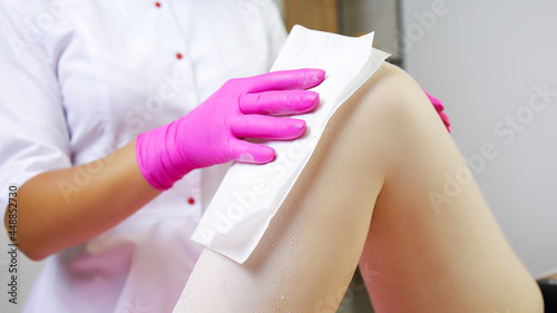 close-up of the hand of a sugar epilation master who applies a napkin to the model s leg.