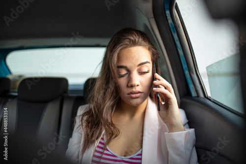Sad young woman looking through the car window. Bored woman in a car. Pensive woman looking out of a car window. Sad young woman in the car talking with smartphone © Dragana Gordic