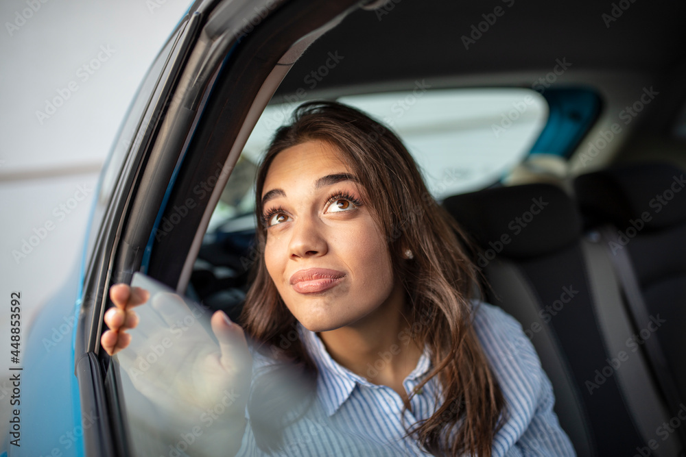 A Latina business woman rides in a crowdsourced taxi, having requested a pick up and drop off on her smartphone. Female business executive travelling by a cab