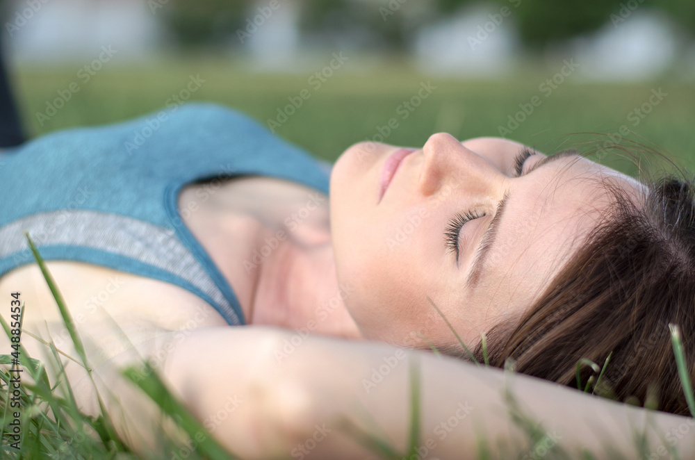Beautiful young sportswoman is resting after training. Young woman lies on the grass in the park Beautiful young sportswoman is resting after training. Young woman lies on the grass in the park