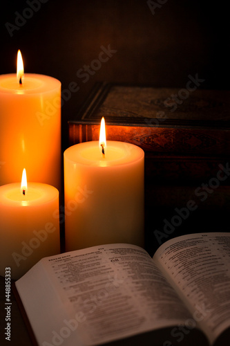 Three Pillar Candles Burning in a Dark Room with a Bible
