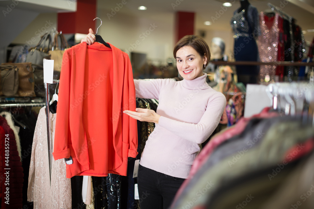 Smiling customer deciding on jersey cardigan in women cloths shop