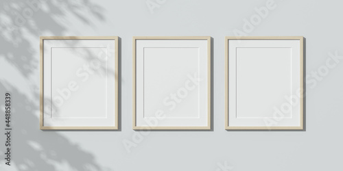 Three wooden frames on white wall. Triptych. 3D render wooden frame mock up. Empty interior. 3D illustrations. 3D design interior. Template for business. Passe partout frame. Shadow on the wall.	
 photo