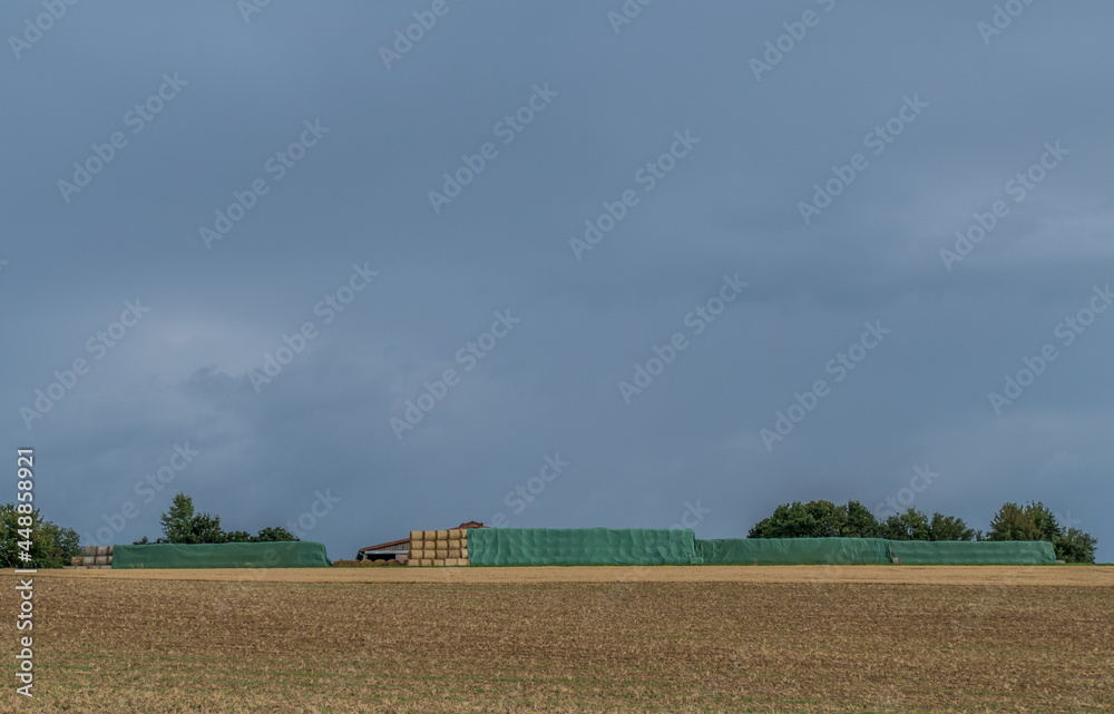 Strohrollen lagern vor einer landwirtschaftlichen Lagerhalle