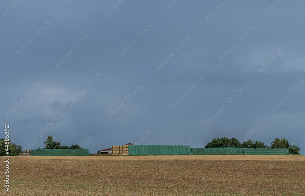 Strohrollen lagern vor einer landwirtschaftlichen Lagerhalle Strohrollen lagern vor einer landwirtschaftlichen Lagerhalle