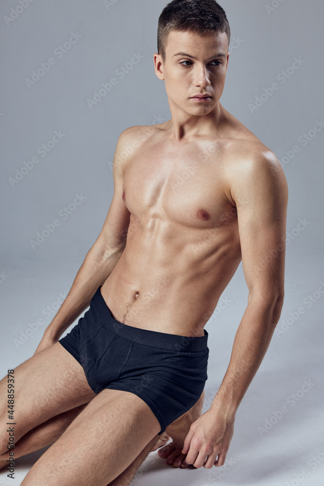 Naklejka premium handsome man with pumped up abs black panties posing cropped view model