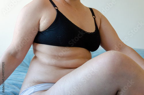 a woman fat overweight body sitting  seen by side  using bikini only