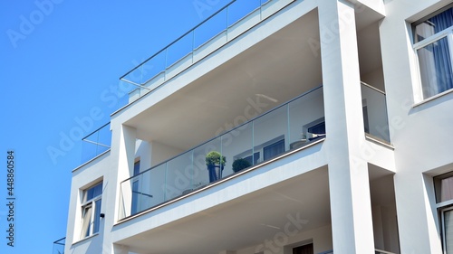Modern white facade of a residential building with large windows. View of modern designed concrete apartment building.