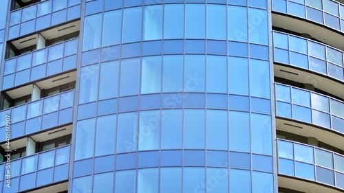 Glass and steel. Mirrored facade of modern office building with blue sky.