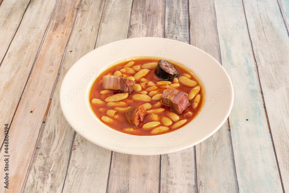 Popular Spanish recipe for Asturian fabada with large white beans, bacon cubes, chorizo chunks and black pudding to cook