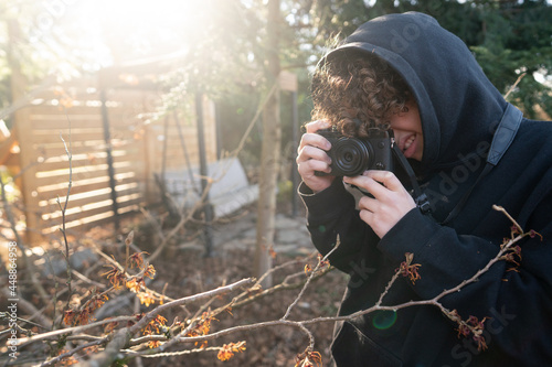 Boy with camera taking photo of tree blossom
 photo