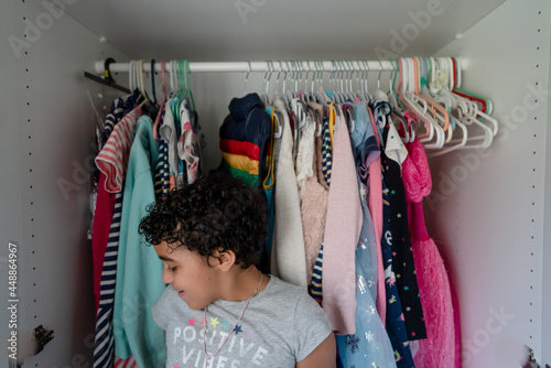 Girl leans against clothes in closet photo