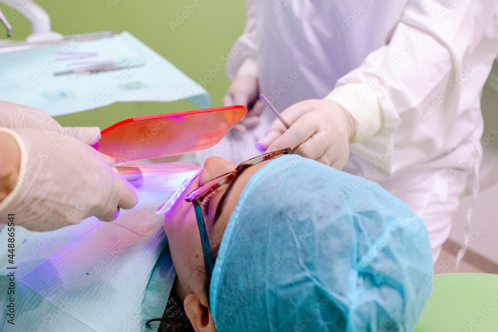 Crop dentists whitening teeth of boy with UV lamp Crop dentists whitening teeth of boy with UV lamp