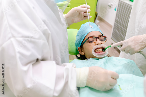 Crop dentists curing teeth of boy photo