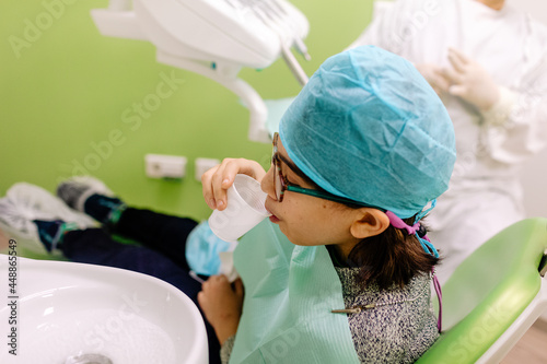 Mixed race boy sipping water in dental office