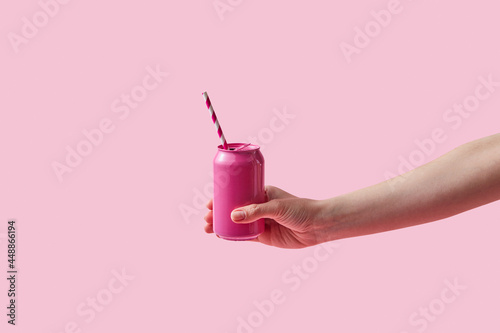 Woman holding pink soda can with paper straw photo