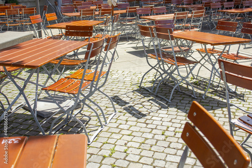 View of unoccupied wooden tables and chairs outside on a sunny day