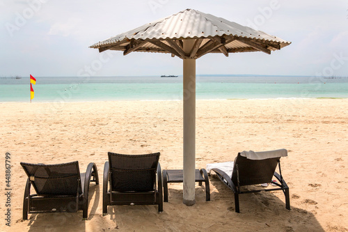 a couple of lawn chairs sitting on top of a sandy beach