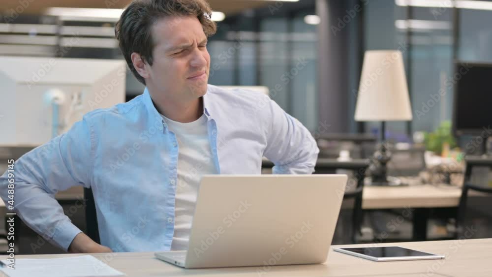 Man having Back Pain while using Laptop in Office Man having Back Pain while using Laptop in Office