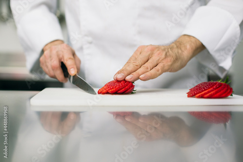Chef slicing strawberries with kitchen knife  photo