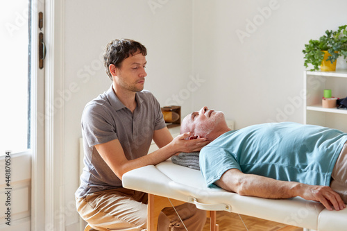 An osteopath exerting pressure on patient's neck photo