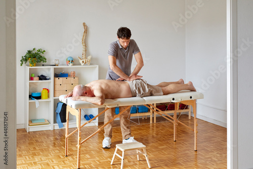 An osteopath massaging patient's coccyx photo