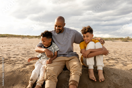 Father sitting on the sand beach with his children