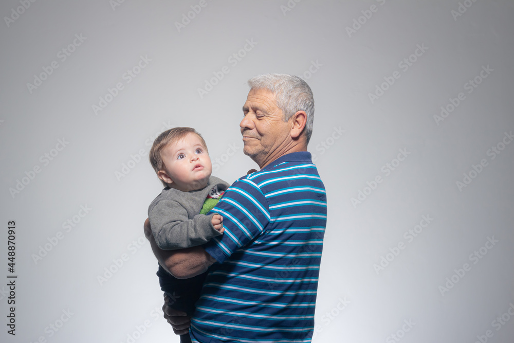 Grandfather holding his baby grandson who is curious looking up Grandfather holding his baby grandson who is curious looking up