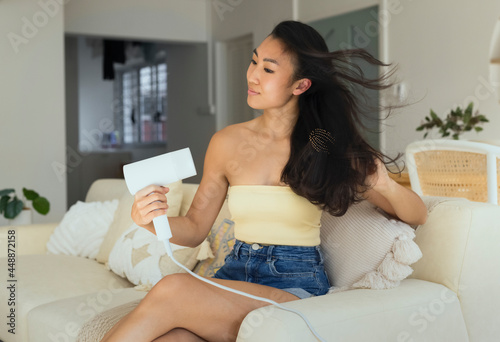 asian singaporean woman using blow dryer