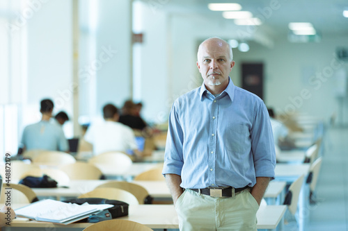 Serious senior businessman standing in an open plan office