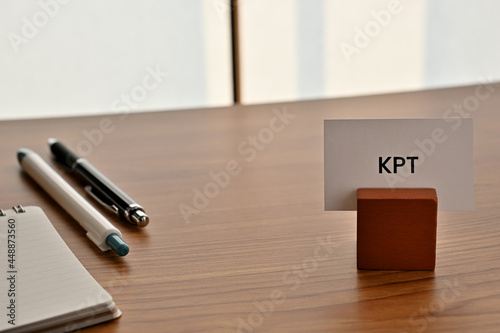 There is a card on paper stand with the word of KPT which is an abbreviation for Keep Problem Try on the desk with a pen. photo