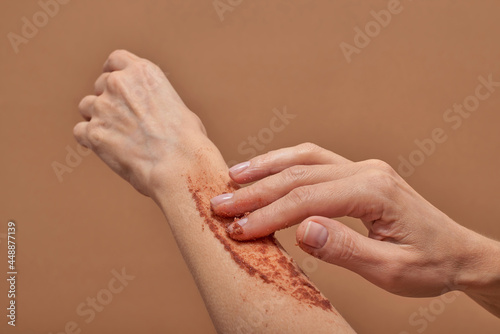 Unrecognizable female applying scrub on arm photo